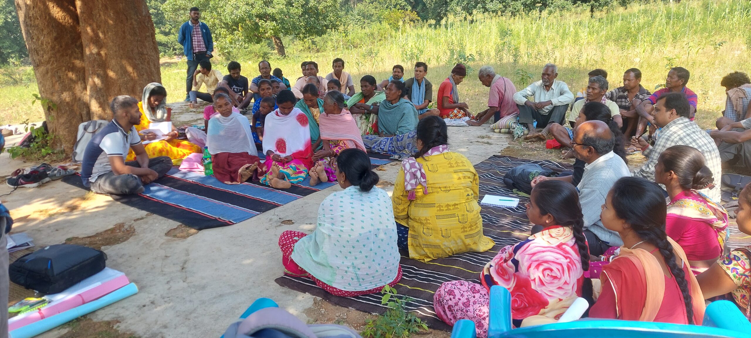Villagers of Dhodrobaru sit with WELL Labs team members under a tree, holding discussions on crop water budgeting