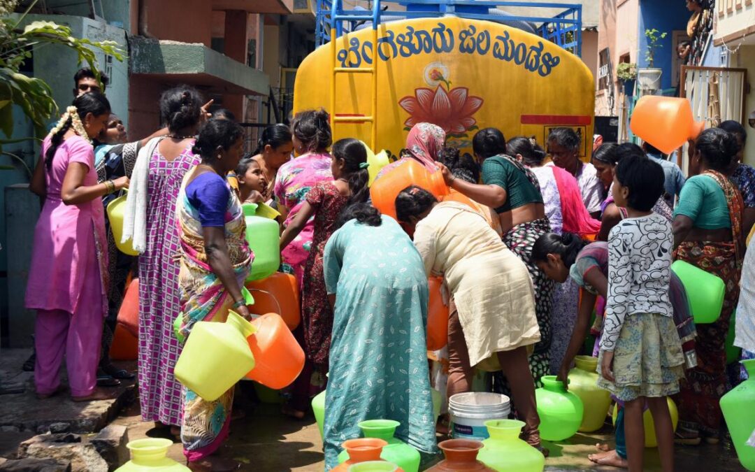 People gather with pots around a water tanker vehicle in Bengaluru, India.