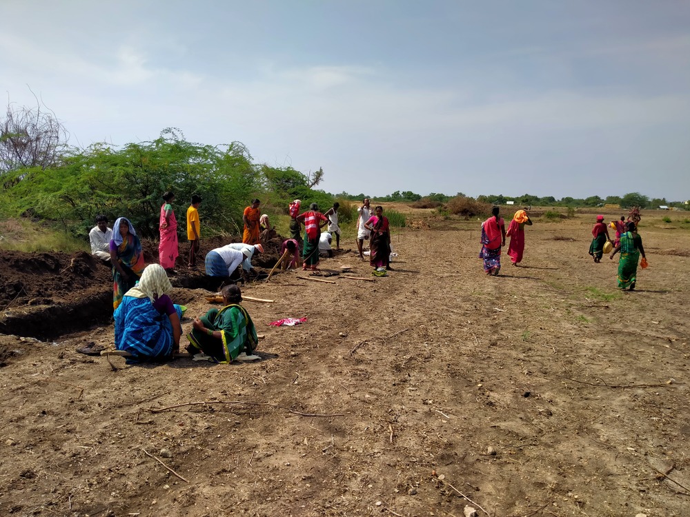 Group of twenty farmers working/sitting in a barren field