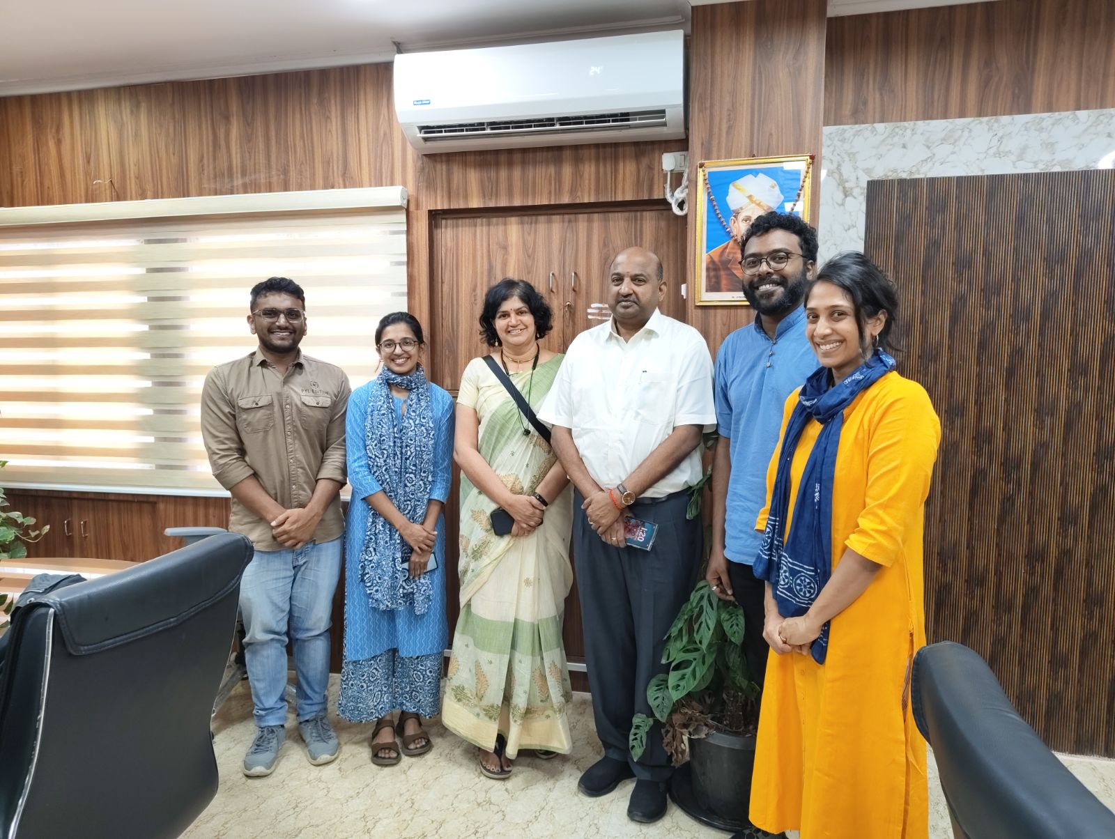 6 people standing next to each other in an office space