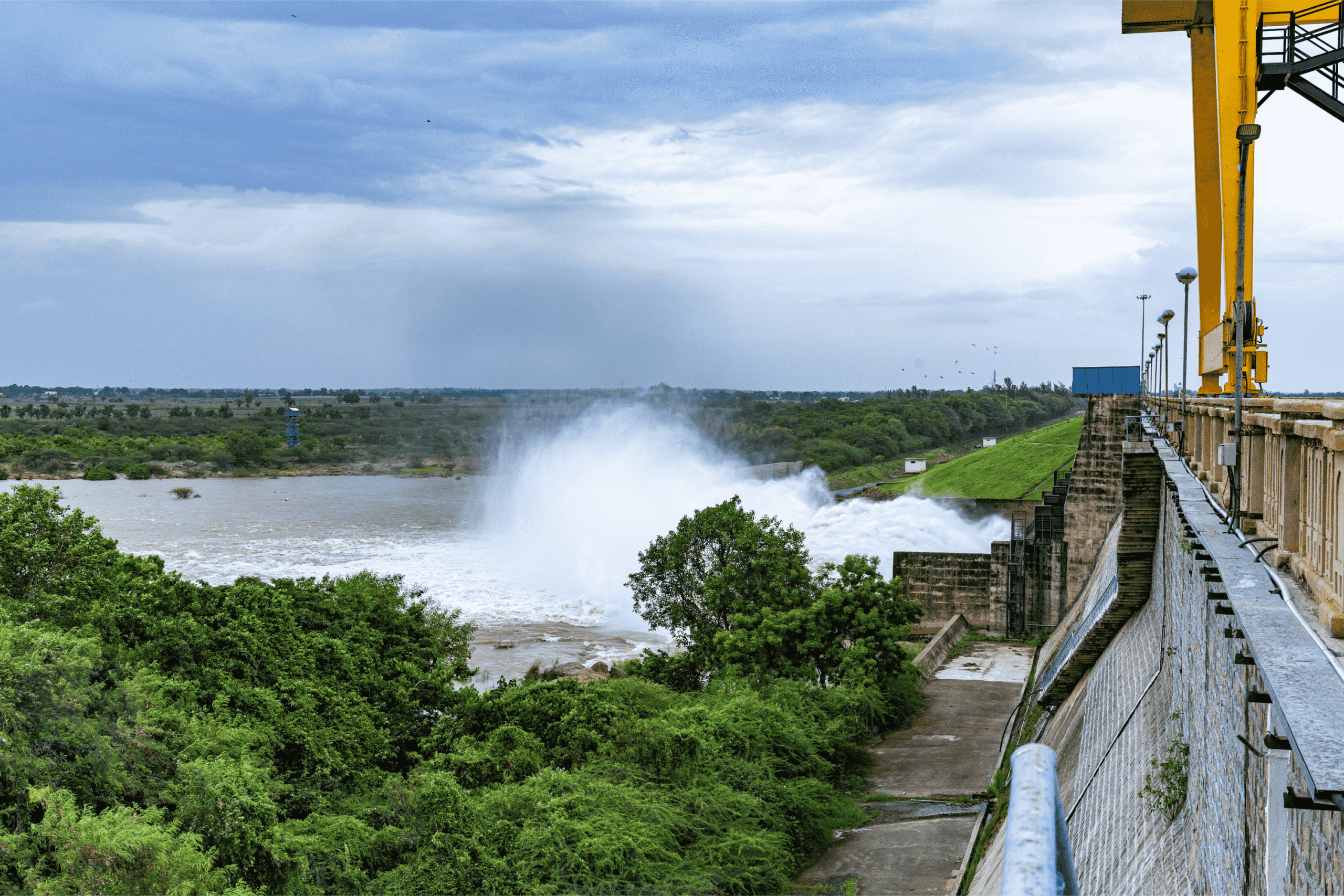 A view of a dam on the right and its downstream surrounded by verdure on the left